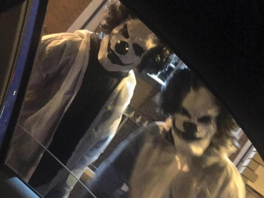 Two clowns allegedly carrying weapons stand outside of a car window.