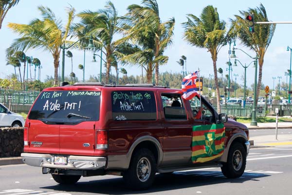 Maui residents are seen showing their activism by waving Hawaiian flags from their car.