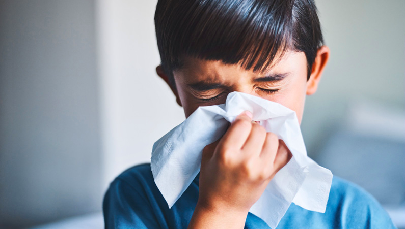 Caption: A young boy blows his nose to help clear his congested nose.