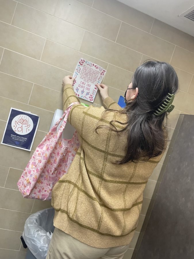 Junior Student Kahaʻi Duquette sets up a take-one-leave-one station in the womens auditorium bathroom.